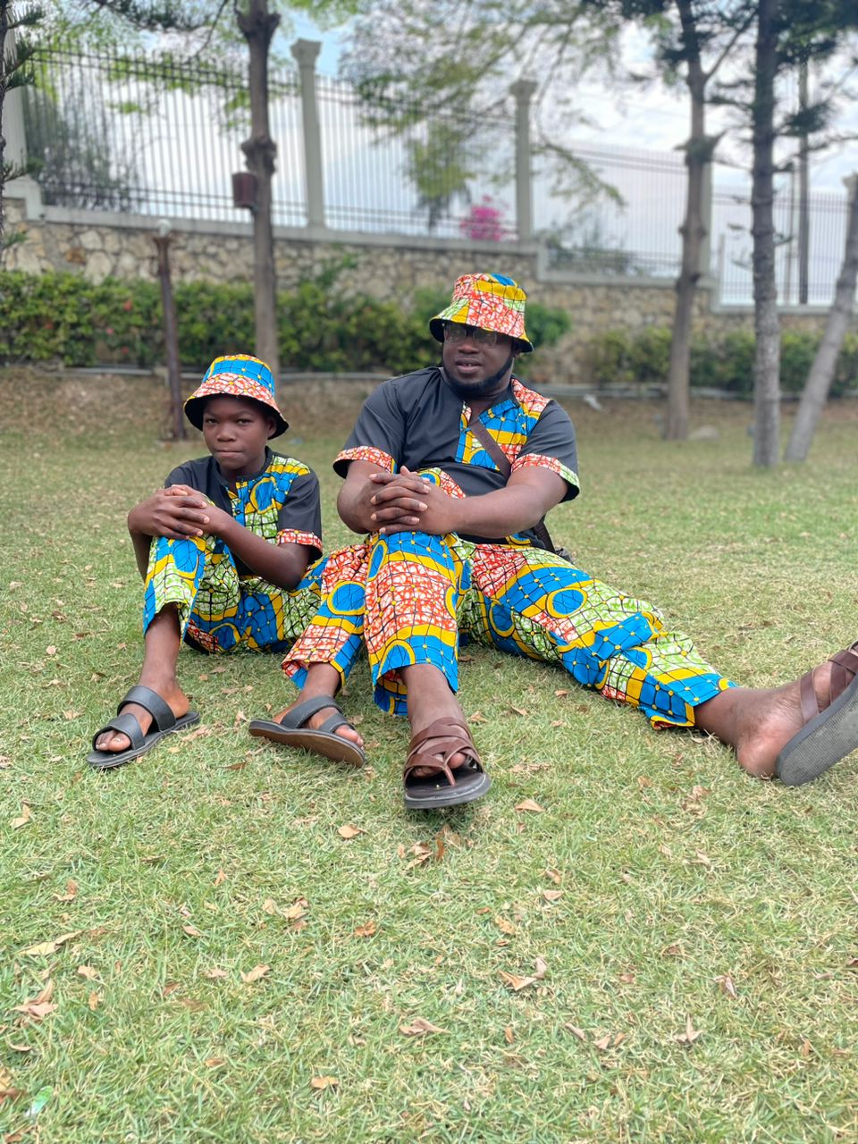 Fr. Luckson et un enfant assis sur la pelouse